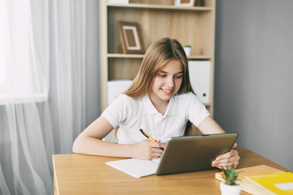 An attractive student is studying an online course and taking notes while preparing