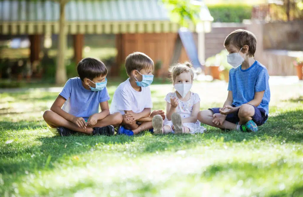 Young children in protective masks on faces in park